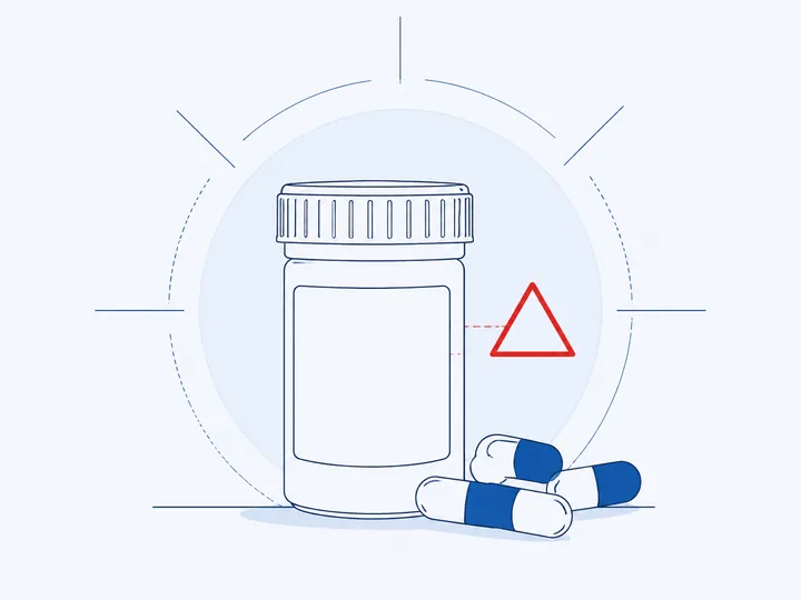 A prescription bottle with a blank label beside loose capsules
